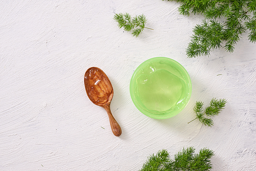 spa setting with cosmetic cream, gel, bath salt and fern leaves on white wooden table background