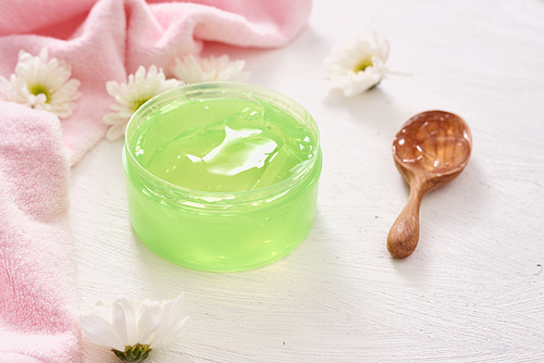 spa setting with cosmetic cream, gel, bath salt and fern leaves on white wooden table background