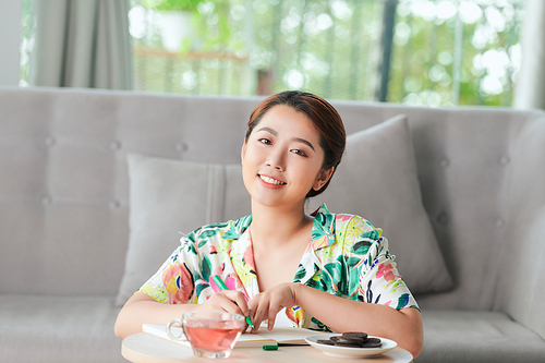 Beautiful young asian woman sitting on floor and writing a diary.