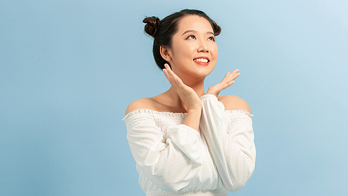 Surprised happy beautiful woman looking sideways in excitement. Isolated on blue background