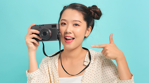 Pretty cool young woman model with retro film camera over blue background