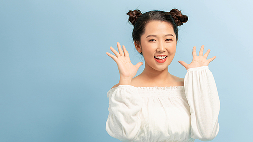 Surprised young woman shouting over blue background. Looking at camera