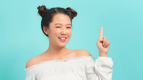 Happy asian woman having idea and winks at the camera over blue background