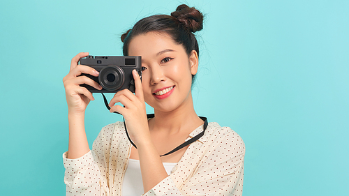 Pretty cool young woman model with retro film camera over blue background