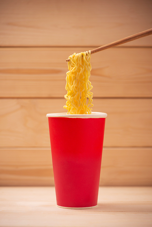 Eating Instant noodles in cup with a wooden chopstick.