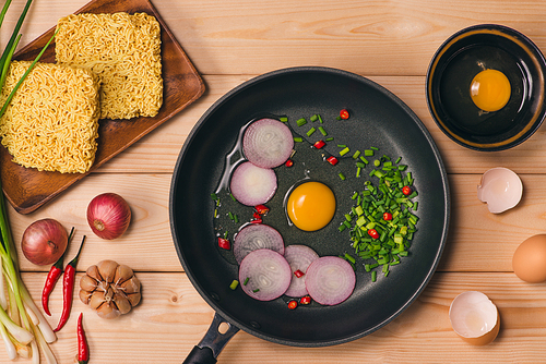 Instant noodles for cooking and eat in the dish with eggs and vegetables on wooden background.