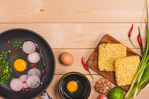 Instant noodles for cooking and eat in the dish with eggs and vegetables on wooden background.