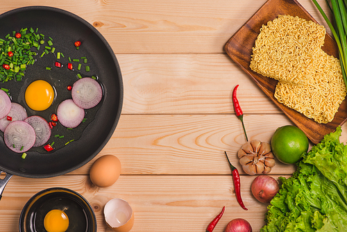 Instant noodles for cooking and eat in the dish with eggs and vegetables on wooden background.