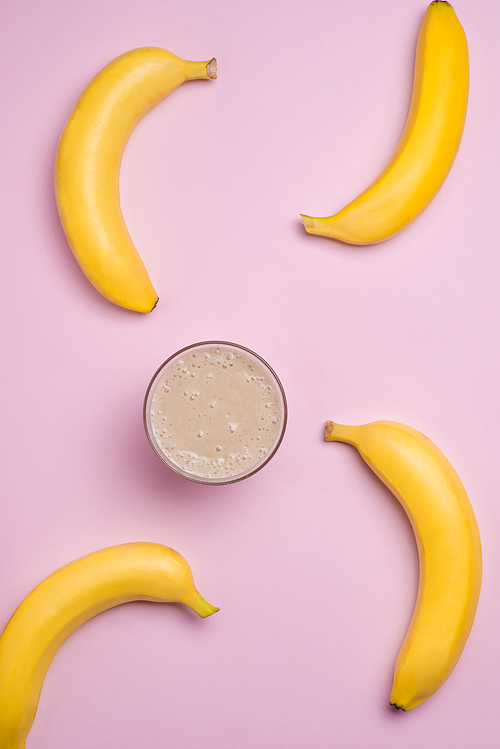 Top view. Group of bananas and banana smoothie on pink background.