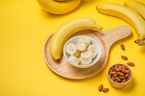 A banch of bananas with almonds on yellow background.