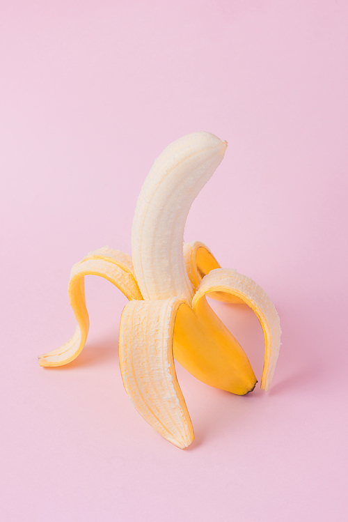 Fresh peeled banana on pink background