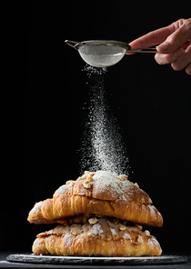 baked croissants on a black wooden board sprinkled with powdered sugar