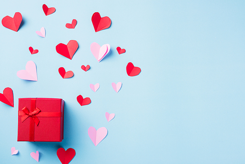 Valentines' day background. Red gift box postcard and paper flying elements hearts cut greeting gift card isolated on blue background, Symbol of love. Top View Happy Mother's, Valentine's Day concept