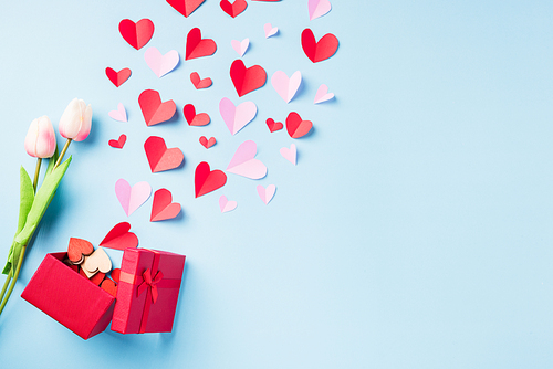 Valentines' day background. Red gift box postcard and paper flying elements hearts cut greeting gift card isolated on blue background, Symbol of love. Top View Happy Mother's, Valentine's Day concept