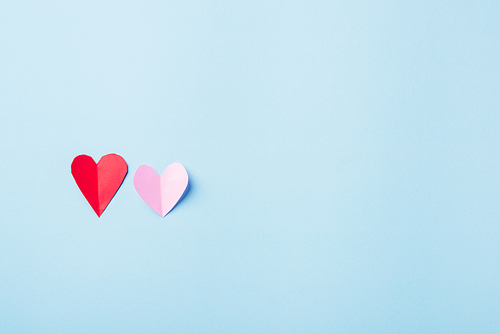 Valentines' day background. Beautiful red and pink paper hearts cut composition greeting card isolated on blue background with copy space, Symbol of love Top View from above