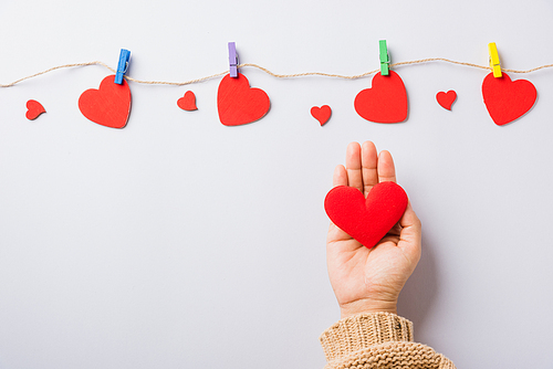 Valentine's day and birthday. Woman hands holding red heart present decorated surprise on white background, Female's hand hold gift heart on hands, Top view flat lay composition