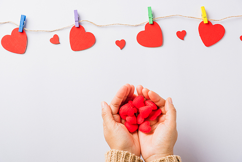 Valentine's day and birthday. Woman hands holding red heart present decorated surprise on white background, Female's hand hold gift heart on hands, Top view flat lay composition