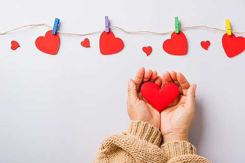 Valentine's day and birthday. Woman hands holding red heart present decorated surprise on white background, Female's hand hold gift heart on hands, Top view flat lay composition