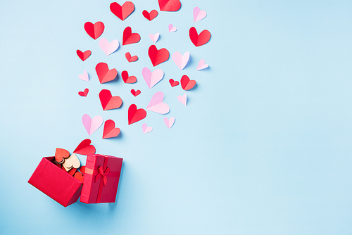 Valentines' day background. Red gift box postcard and paper flying elements hearts cut greeting gift card isolated on blue background, Symbol of love. Top View Happy Mother's, Valentine's Day concept