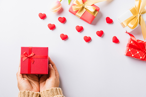 Valentine's day and birthday. Woman hands holding gift or present box decorated and red heart surprise on white background, Female's hand hold gift box package in craft paper Top view flat lay