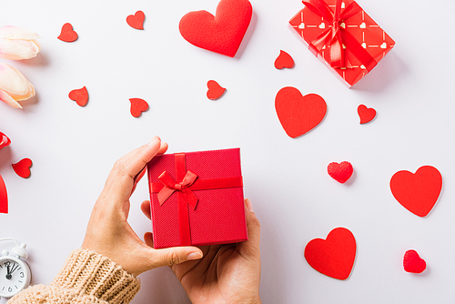 Valentine's day and birthday. Woman hands holding gift or present box decorated and red heart surprise on white background, Female's hand hold gift box package in craft paper Top view flat lay