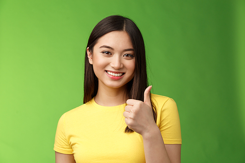 Close-up happy motivated good-looking asian woman give thumb-up smiling, approving excellent effort, like good choice, accept terms, recommend product, like idea, green background. Copy space