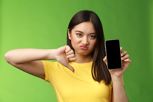 Close-up disappointed upset asian girl judging bad awful app, show smartphone screen, thumb-down grimacing displeased, give negative feedback, cannot stand ex-boyfriend new girlfriend.