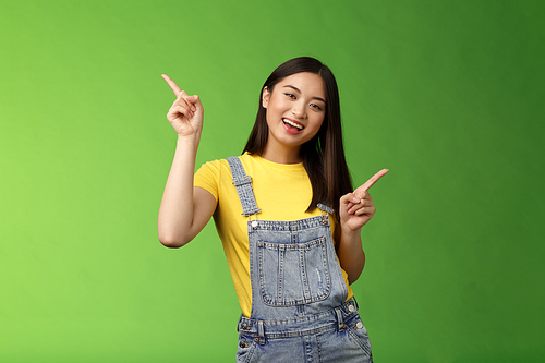 Friendly stylish good-looking upbeat teenage asian brunette, dancing joyfully showing few choices, shopping online easy picking products, pointing sideways left right, smiling enthusiastic.