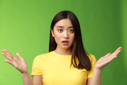Frustrated shocked concerned asian female friend, shrugging spread hands sideways full disbelief, gasping perplexed, tough situation, look worried empathy, stand green background upset.