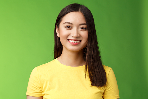 Optimistic cute carefree asian girl taking care skin condition, smiling satisfied grin happily, enjoy funny outgoing conversation, stand green background upbeat, communicate pleasantly.