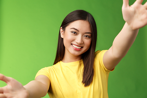 Close-up cheerful cute asian friendly woman spread hands holding camera both arms, smiling broadly, taking selfie, communicate family digital tablet study abroad, feel happy green background.