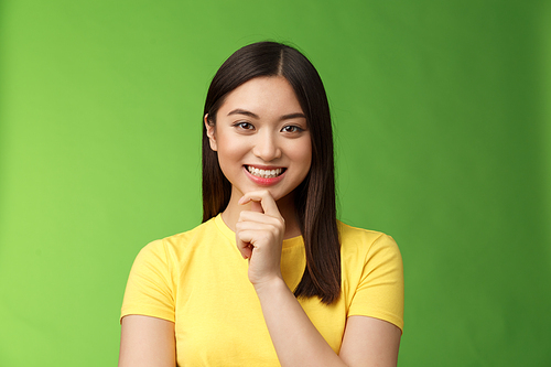 Smart assertive creative asian female student make interesting research assumption, smiling intrigued touch chin thoughtful, have good plan idea, thinking, ponder choices, green background.