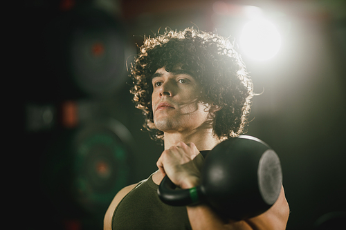 A muscular man is doing hard training with kettlebell at the gym.