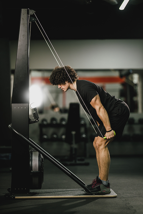 A young muscular man is doing hard ski rope crossfit training in the gym.