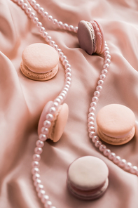 Girly, bakery and branding concept - Sweet macaroons and pearls jewellery on silk background, parisian chic jewelry, French dessert food and cake macaron for luxury confectionery brand, holiday gift