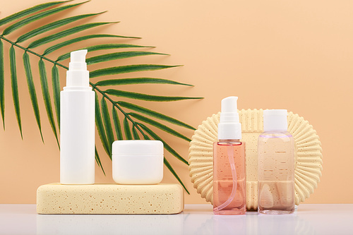 Cosmetic set with mask, cream and lotion against beige background with palm leaf. Concept of eco organic cosmetics with natural ingredients or summer skin care products with sunscreen