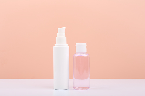 Cosmetic tubes with face cream and lotion for skin cleaning and exfoliating against bright pink background with copy space. Concept of daily skin care and beauty