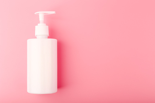 Top view of shower or intimate gel in white unbranded tube on pink background with copy space. Concept of hygiene, beauty products and pampering