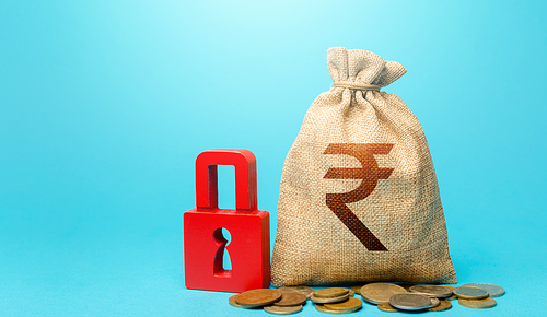 Indian rupee money bag and red padlock. Blocking bank accounts and seizing assets. Freezing of pension savings. Cash flow monitoring. Tight government control over the financial system.