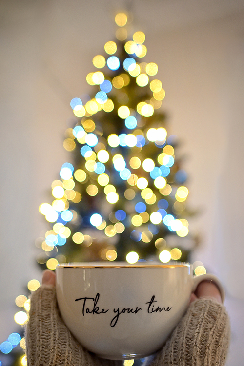 Conceptual Take your time Girl Holding a Cup of Tea and Christmas Tree Bokeh