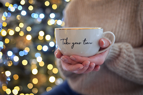 Conceptual Take your time Girl Holding a Cup of Tea with Holidays Bokeh Lights