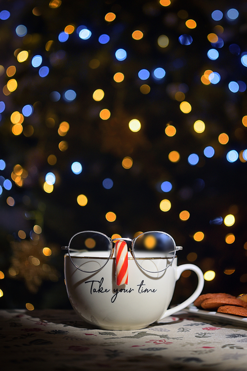 Conceptual Tea Cup Wearing Glasses On Candy Cane Nose with Holidays Bokeh Lights