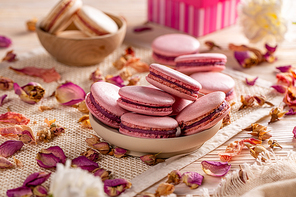 Delicious almond cookies in wooden bowl decorated with rose petals