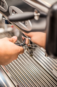 The hand of a man is operating a professional coffee machine