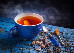 Cup with black tea on blue wooden background