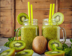 Healthy fresh kiwi smoothie in glass on a wooden background