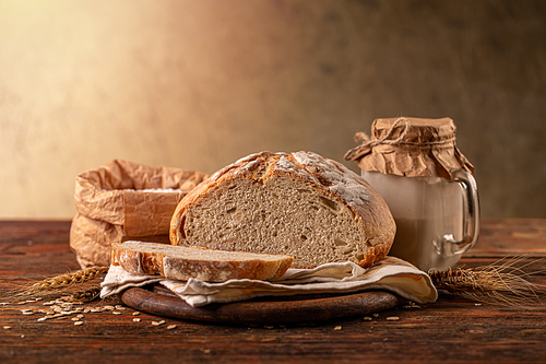 Cut loaf of artisanal wheat bread in a wooden background