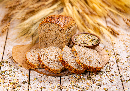 Bread with different seeds, pumpkin, poppy, flax, sunflower, sesame, on wooden background