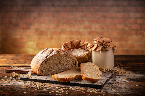 Active wheat sourdough starter in glass jar with bread