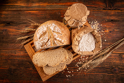 Flat lay of a rustic loaf of bread on an old wooden table.